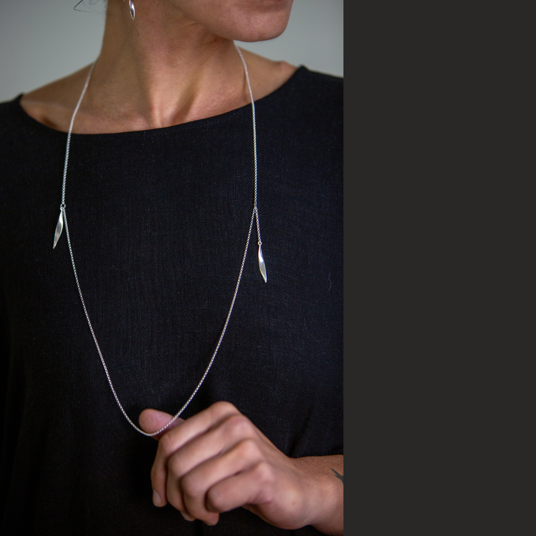 Person wearing a delicate silver necklace with a blurred background
