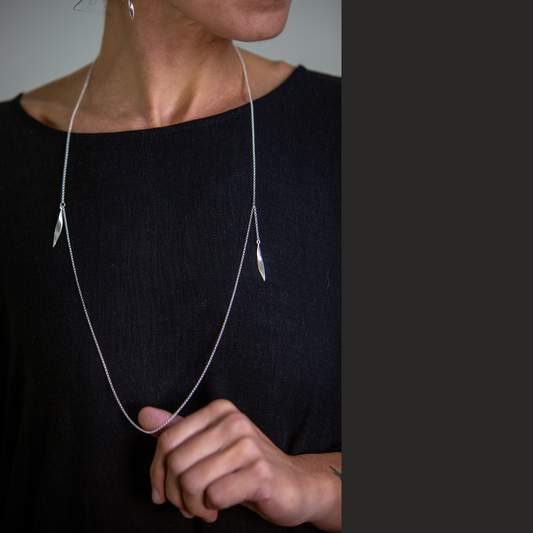 Person wearing a delicate silver necklace with a blurred background